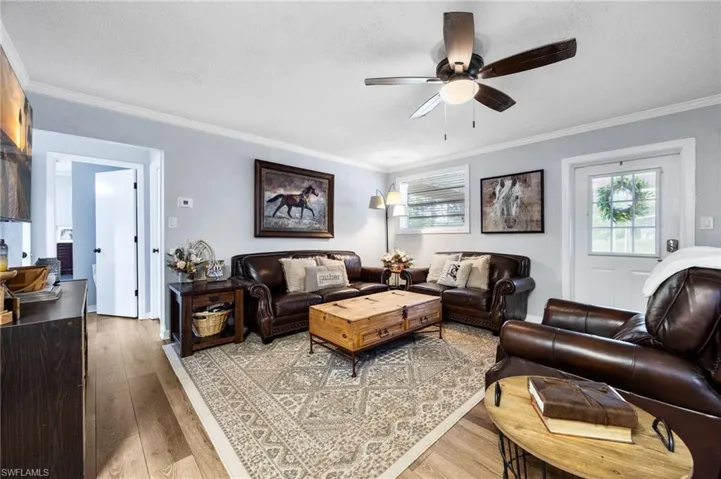 Living room featuring ornamental molding, light wood finished floors, healthy amount of natural light, a textured ceiling, and a ceiling fan