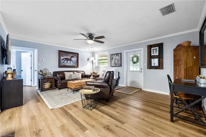 Living area with ornamental molding, light wood-style floors, a ceiling fan, and a textured ceiling