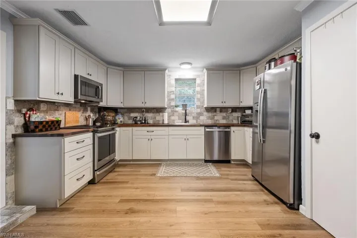 Kitchen featuring stainless steel appliances, light wood-style flooring, and decorative backsplash