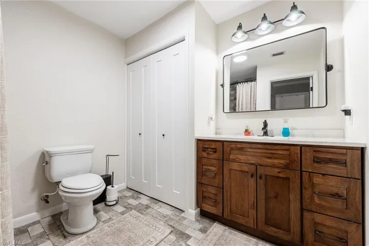 Full bathroom featuring vanity, light stone finish flooring, a closet, and curtained shower