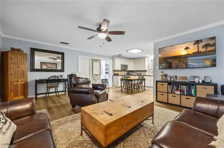 Living area with ornamental molding, wood finished floors, a ceiling fan, and a textured ceiling