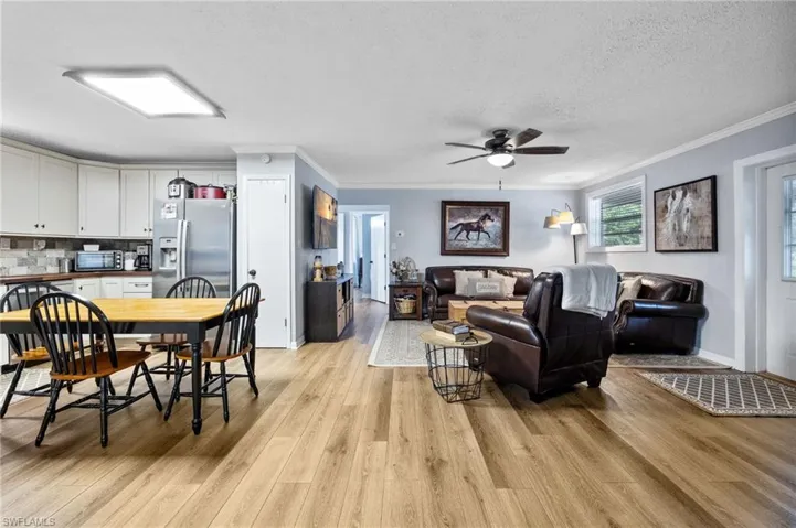 Living room featuring crown molding, light wood-style floors, a textured ceiling, and ceiling fan