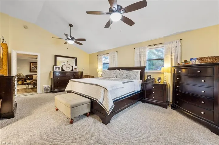 Bedroom with vaulted ceiling, light colored carpet, and ceiling fan