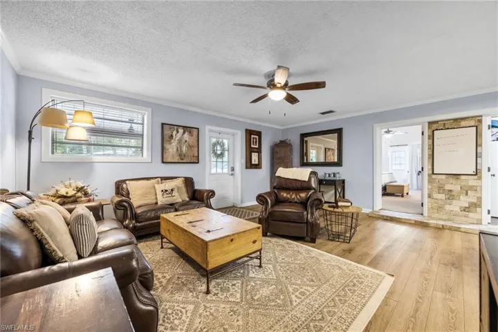 Living area featuring crown molding, hardwood / wood-style flooring, a textured ceiling, and a ceiling fan