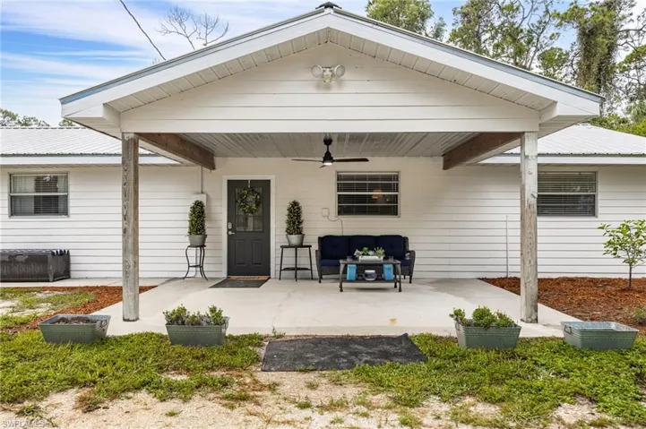 Property entrance with covered porch, a ceiling fan, a metal roof, and an outdoor hangout area