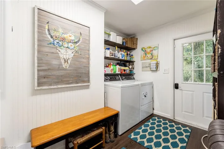 Laundry area with crown molding, wood walls, dark wood-style flooring, and independent washer and dryer