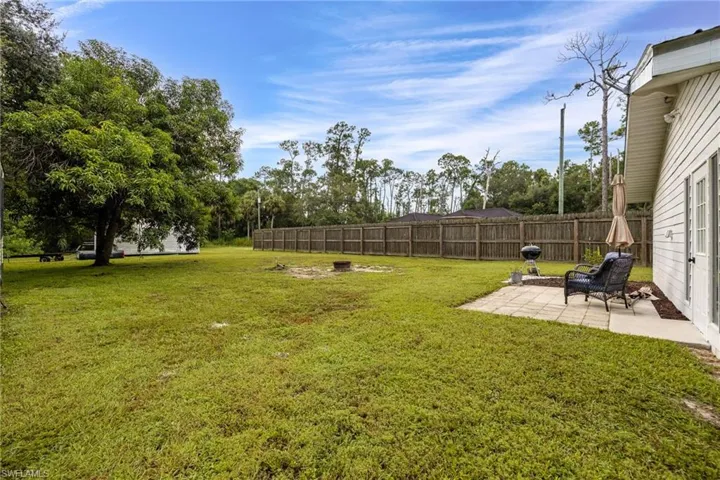 Fenced backyard with a patio and view of wooded area