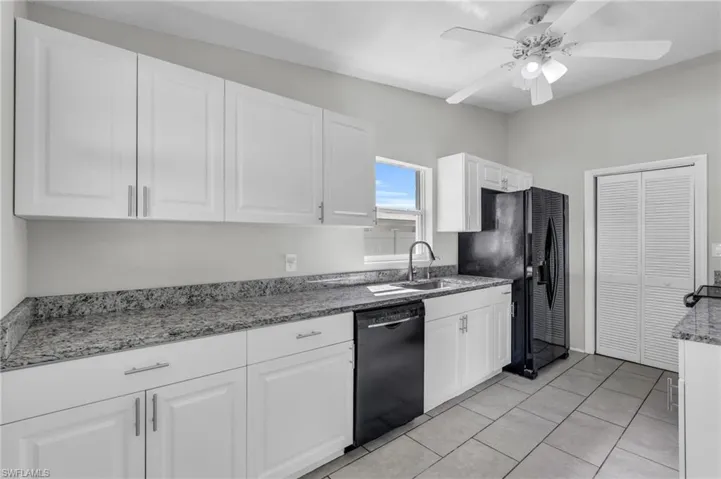 Kitchen featuring ceiling fan, light tile patterned floors, sink, white cabinetry, and black appliances