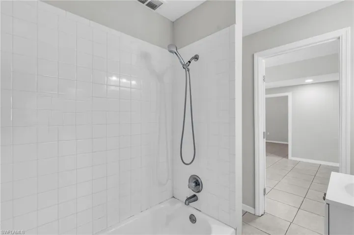 Bathroom with tile patterned flooring, tiled shower / bath combo, and vanity