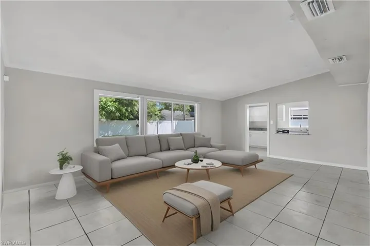 Virtually staged. Tiled living room with vaulted ceiling, sink, and crown molding