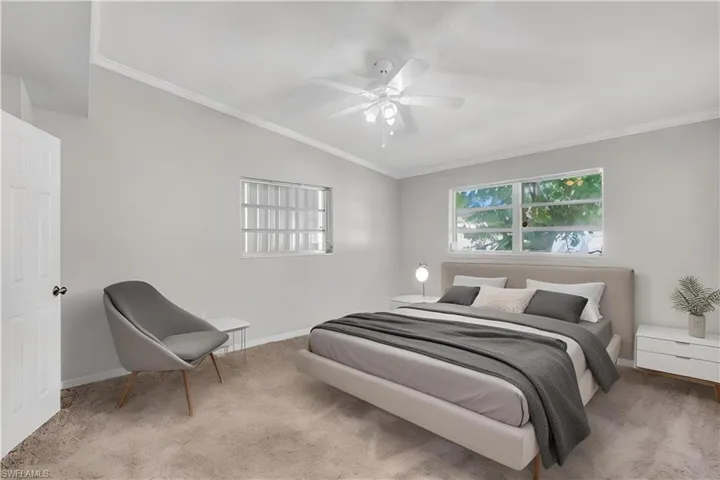 Virtually staged. Carpeted bedroom featuring lofted ceiling, ceiling fan, and crown molding