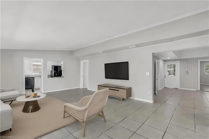Virtually staged. Living room featuring light tile patterned flooring and vaulted ceiling