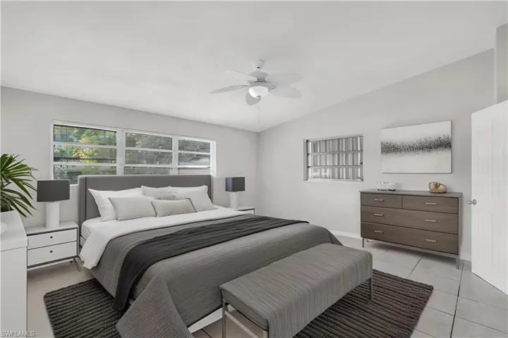 Virtually staged. Tiled bedroom featuring ceiling fan and lofted ceiling