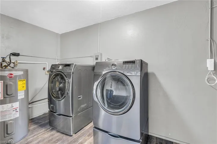 Laundry room featuring water heater, washer and dryer, and hardwood / wood-style flooring
