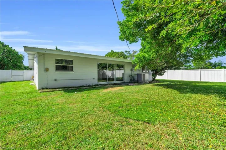 Rear view of property featuring a yard and central air condition unit