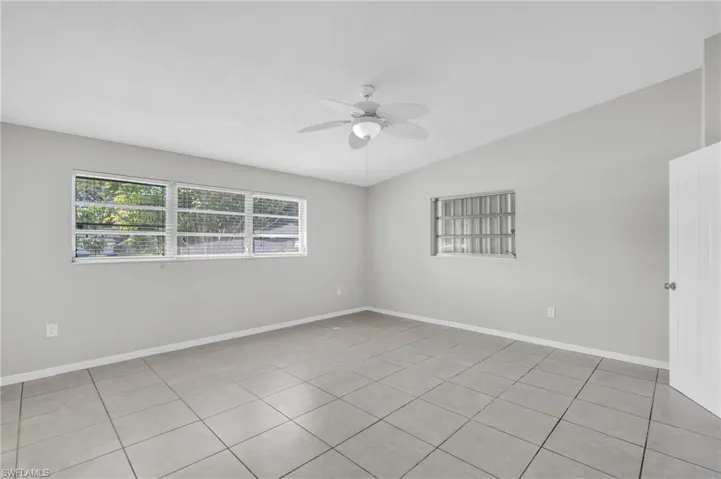 Empty room with lofted ceiling, ceiling fan, and light tile patterned floors