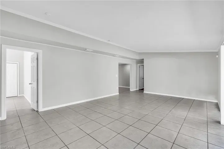 Empty room with crown molding and light tile patterned floors