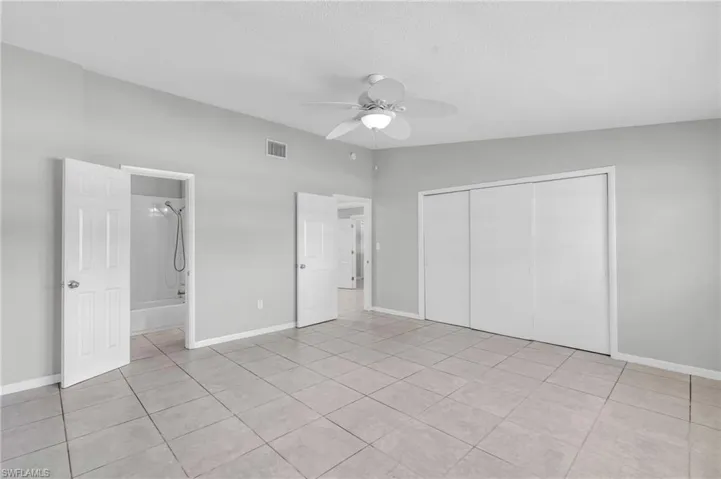 Unfurnished bedroom with ceiling fan, light tile patterned flooring, a closet, and ensuite bathroom