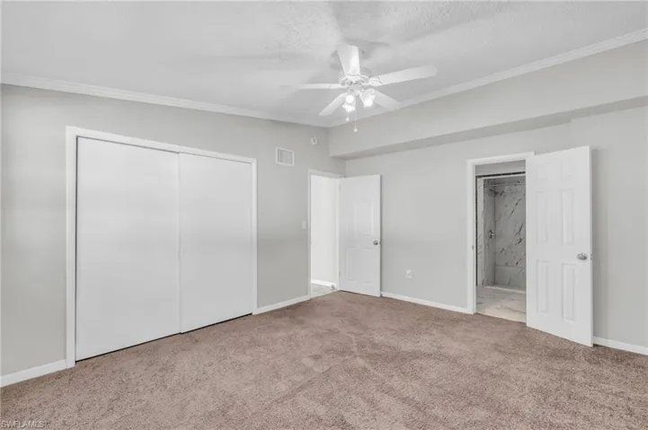 Unfurnished bedroom with a closet, a textured ceiling, light carpet, crown molding, and ceiling fan