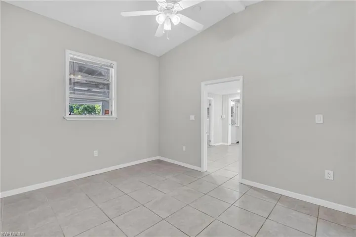 Spare room with ceiling fan, lofted ceiling, and light tile patterned floors