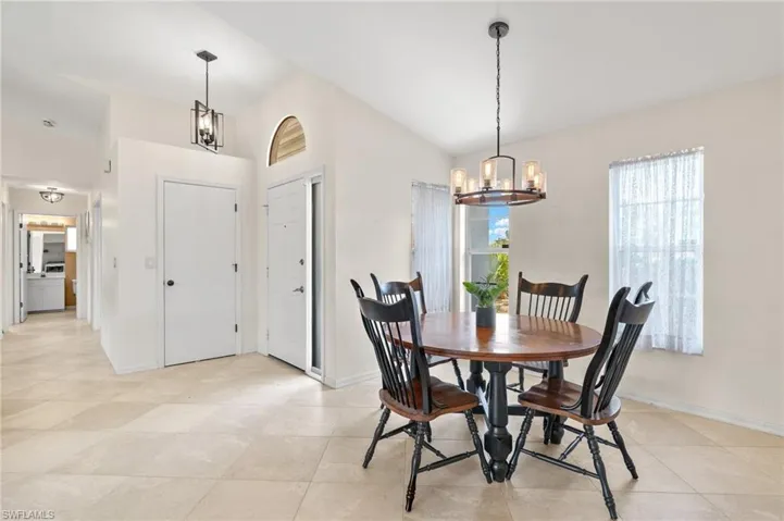Tiled dining room with an inviting chandelier and vaulted ceiling