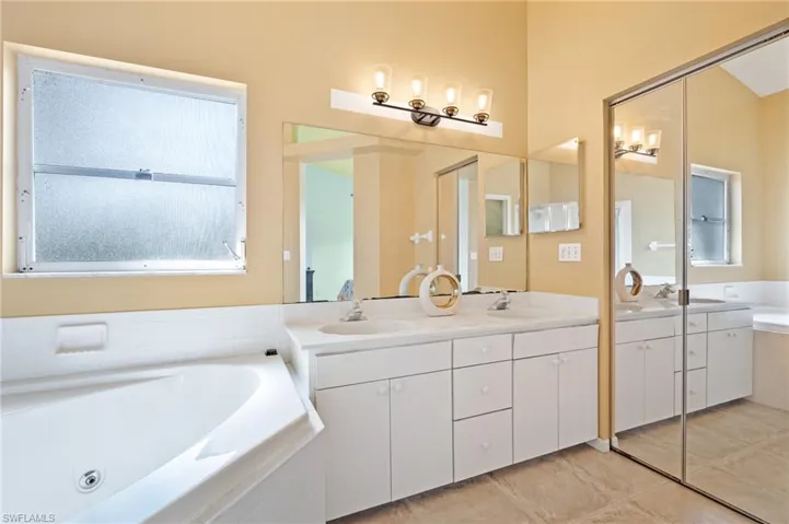 Bathroom featuring tile floors, dual vanity, and tiled tub