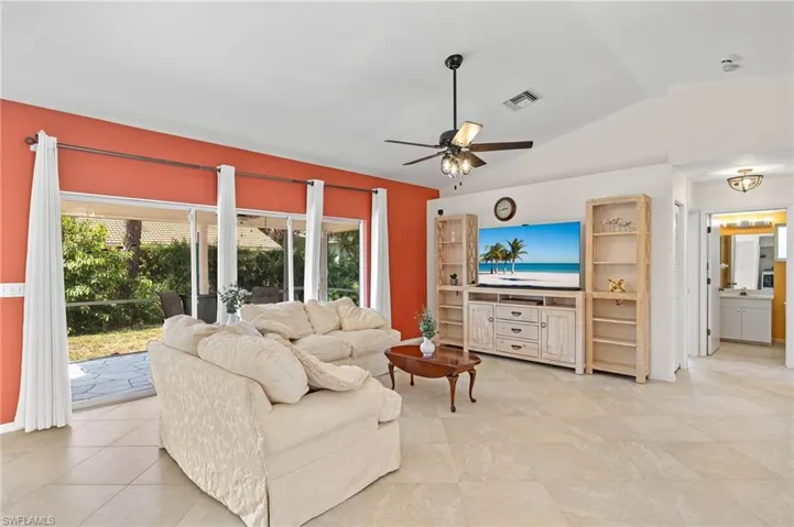 Tiled living room with ceiling fan and lofted ceiling