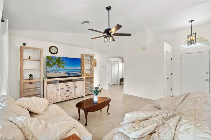 Tiled living room with lofted ceiling and ceiling fan