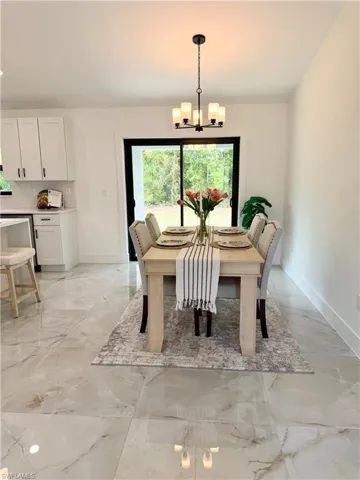 Dining area featuring large-format tile flooring and a multi-light chandelier