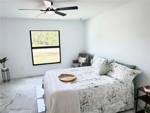 Bright interior space featuring a ceiling fan with integrated lighting, a large window with dark trim, and light-toned walls