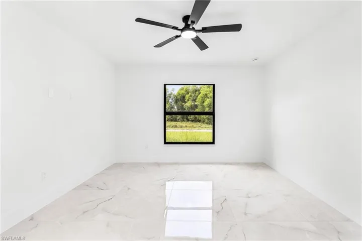 Spare room featuring light marble finish floors and ceiling fan