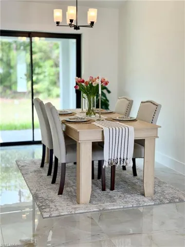 Dining area featuring a contemporary chandelier, large sliding glass doors, white walls, and polished tile flooring