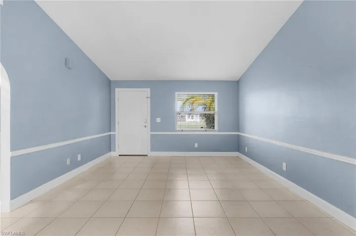 Spare room with lofted ceiling, arched walkways, and light tile patterned floors