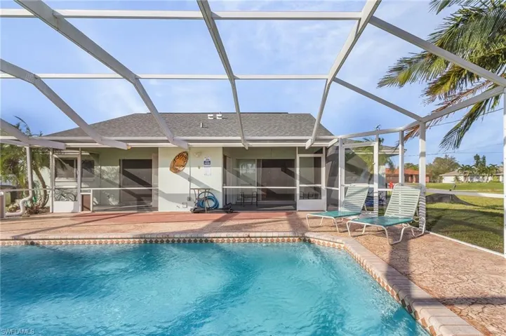 Outdoor pool featuring a sunroom, a patio area, and glass enclosure