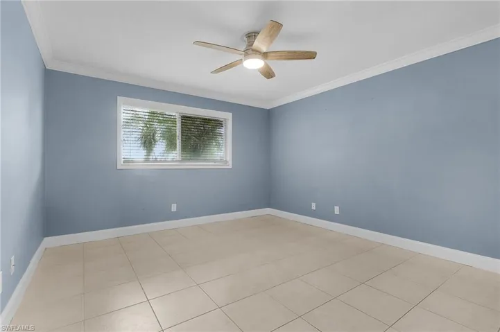 Spare room with ornamental molding, a ceiling fan, and light tile patterned floors