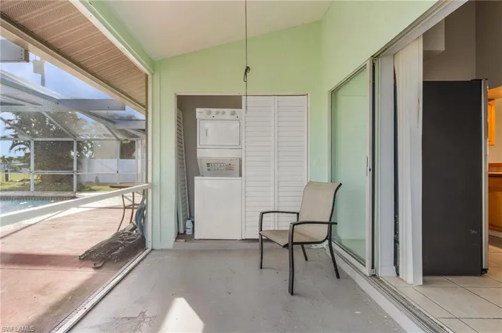 Sunroom / solarium featuring vaulted ceiling, stacked washer / dryer, and a patio area
