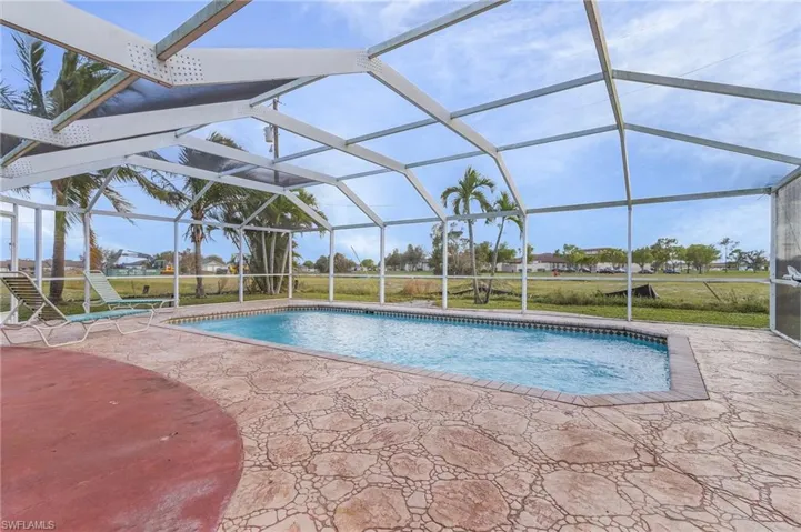 Outdoor pool with a sunroom, a lanai, a lawn, and a patio