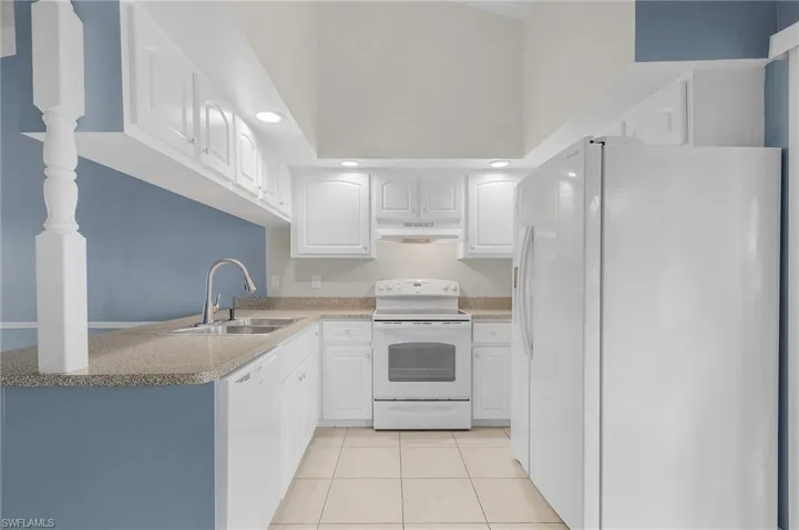 Kitchen featuring white appliances, light tile patterned floors, white cabinetry, recessed lighting, and light countertops