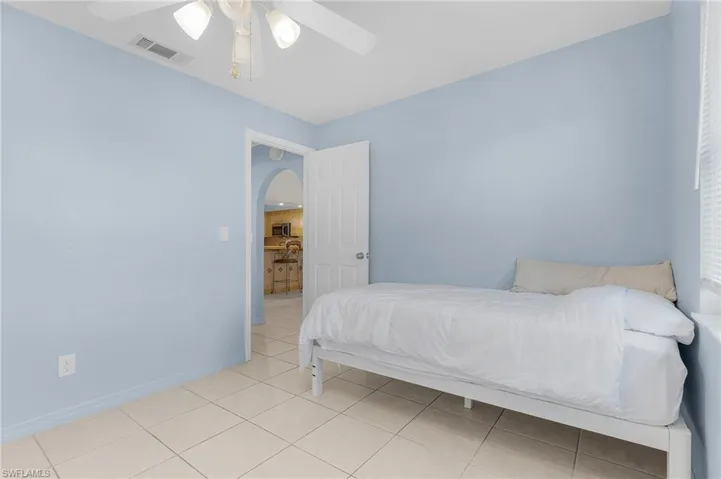 Tiled bedroom with ceiling fan and arched walkways