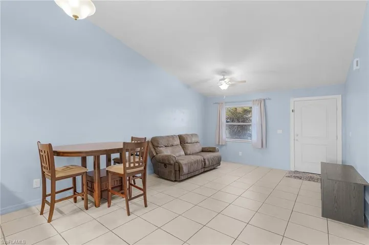 Living area featuring ceiling fan, light tile patterned floors, and lofted ceiling