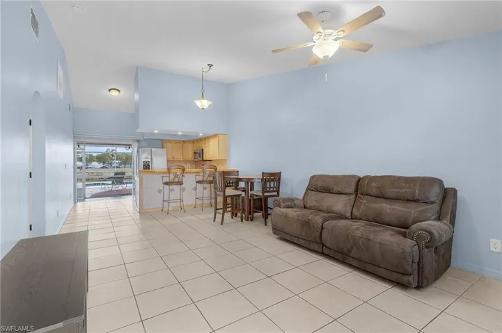 Living room featuring a high ceiling, light tile patterned flooring, a ceiling fan, and arched walkways