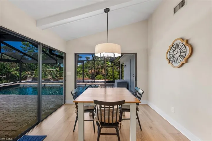 Dining room with lofted ceiling with beams and light hardwood / wood-style floors