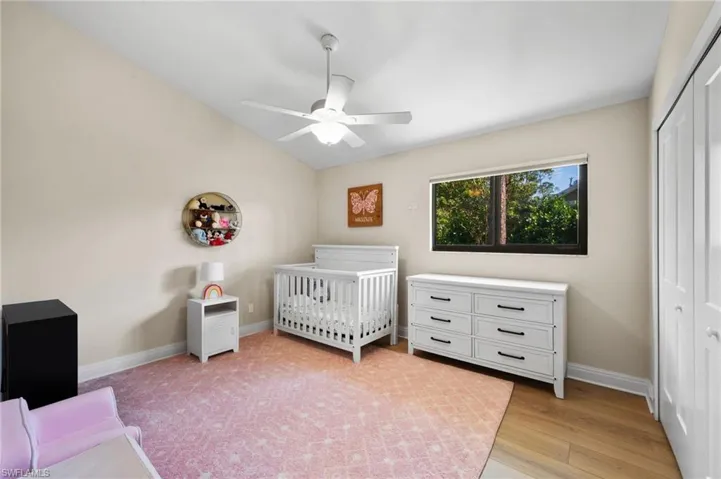 Unfurnished bedroom featuring vaulted ceiling, ceiling fan, a crib, light hardwood / wood-style floors, and a closet