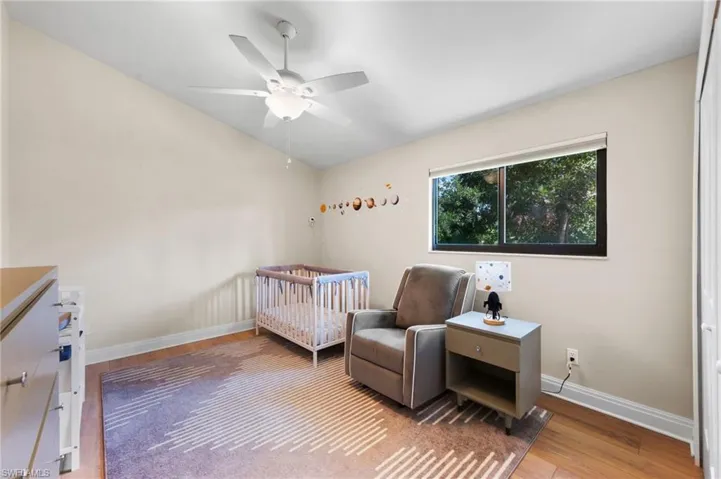 Bedroom featuring ceiling fan, light hardwood / wood-style floors, and a crib
