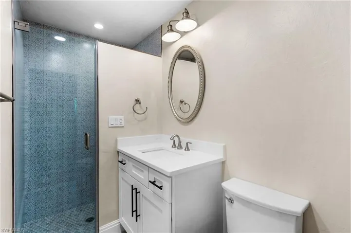 Bathroom with vanity, toilet, and a shower with shower door