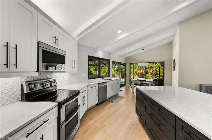 Kitchen featuring backsplash, hanging light fixtures, white cabinets, and stainless steel appliances