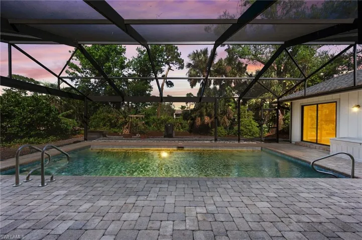 Pool at dusk featuring a lanai and a patio area
