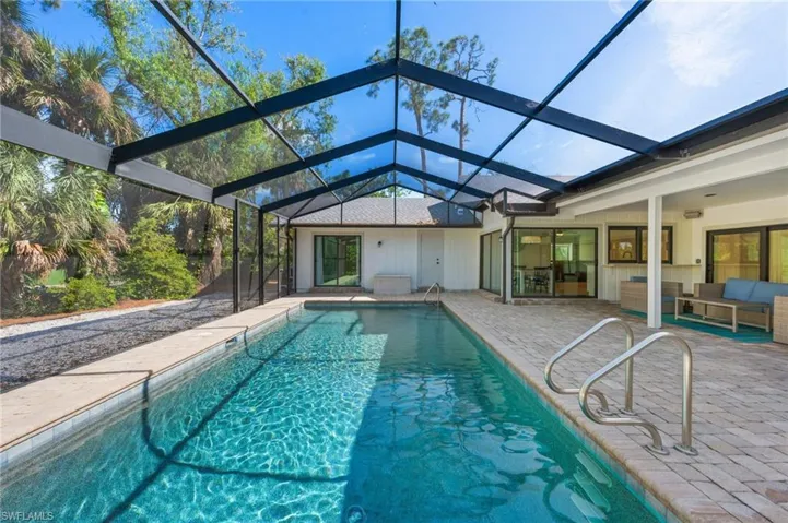 View of pool with a patio, an outdoor hangout area, and glass enclosure