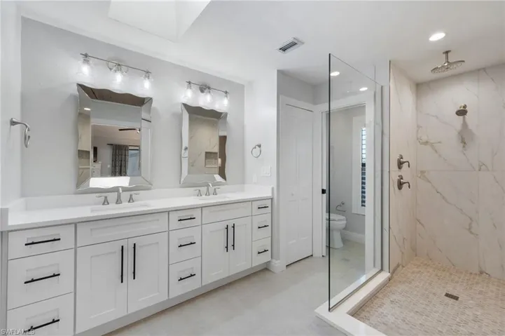 Bathroom featuring tiled shower, vanity, and toilet