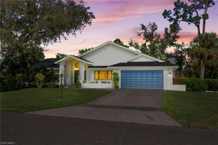 Ranch-style house featuring a lawn and a garage